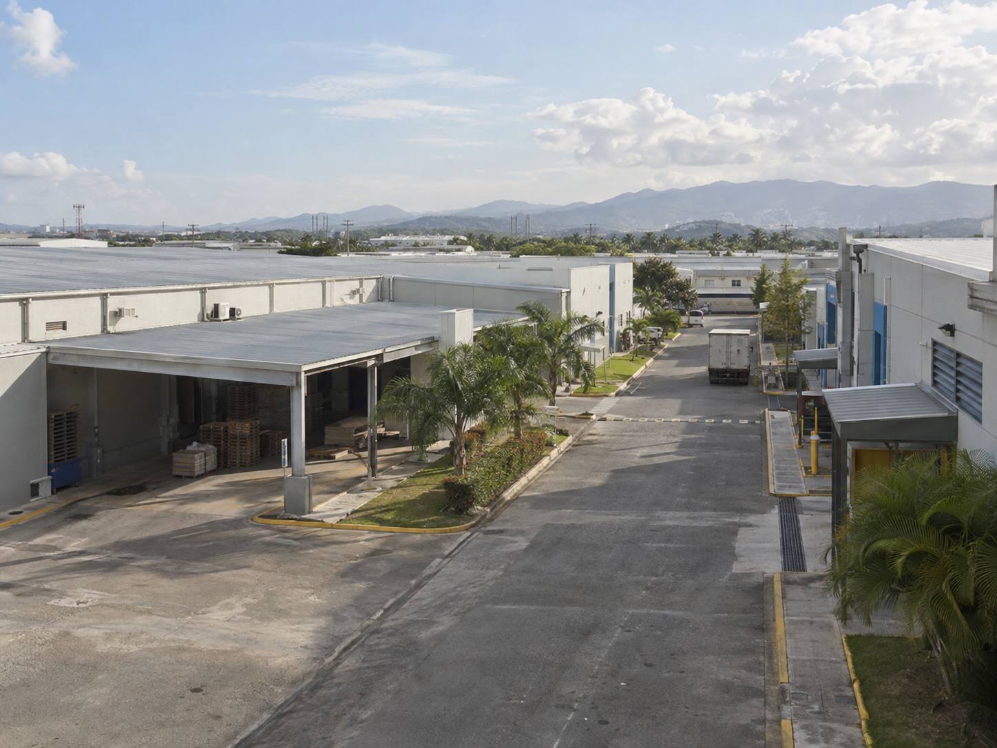 Vista de un parque de zona franca con naves industriales, muelles de carga y la vía interna de circulación